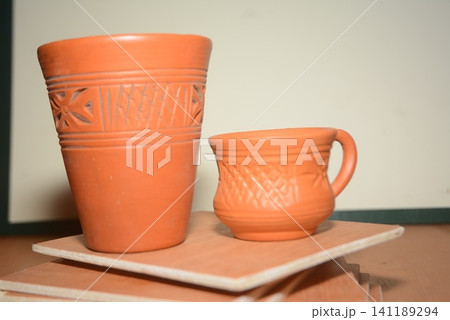 Two traditional decorative terra cotta clay cups on stacked ceramic tiles Two traditional decorative terra cotta clay cups on stacked ceramic tiles 141189294
