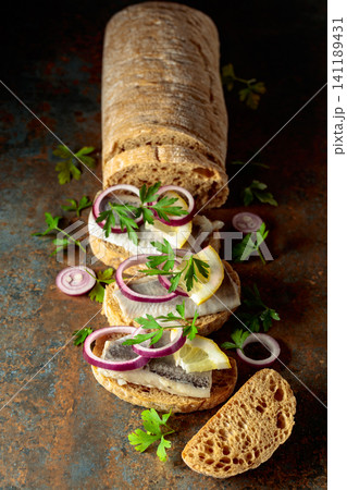 Open sandwiches with herring filet, red onion, lemon, and parsley. Open sandwiches with herring filet, red onion, lemon, and parsley. 141189431