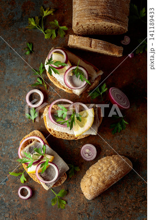 Open sandwiches with herring filet, red onion, lemon, and parsley. Open sandwiches with herring filet, red onion, lemon, and parsley. 141189433