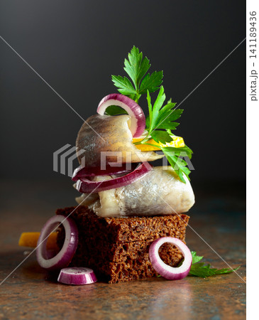 Rye bread canape with herring filet, red onion, lemon, and parsley. Rye bread canape with herring filet, red onion, lemon, and parsley. 141189436