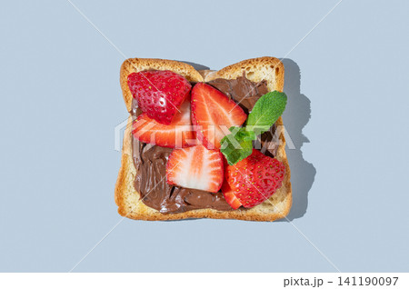 Toasted slice with chocolate cream and strawberries on a blue isolated background 141190097