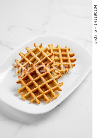 Belgian waffles on a white plate on a marble background. Belgian waffles on a white plate on a marble background. 141190104