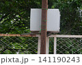White electrical distribution box mounted on wooden pole behind wire mesh fence 141190243