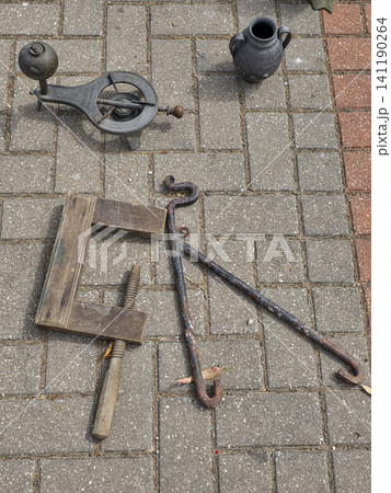 An assortment of old mechanical tools and a portable gas stove are laid out on paving stones. This scene shows the tools resting in a quiet outdoor space. An assortment of old mechanical tools and a portable gas stove are laid out on paving stones. This scene shows the tools resting in a quiet outdoor space. 141190264
