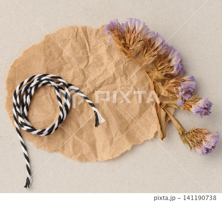 A composition of dried flower sprigs and black and white lace on a sheet of crumpled craft paper A composition of dried flower sprigs and black and white lace on a sheet of crumpled craft paper 141190738