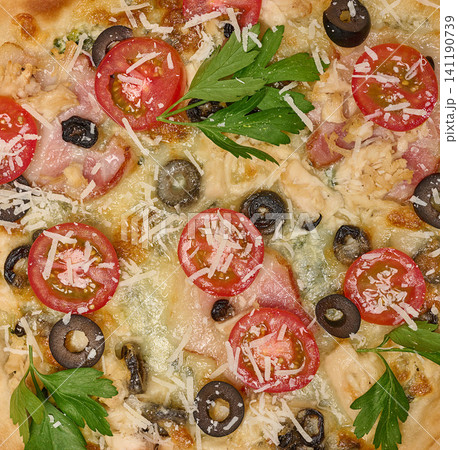 Close-up of delicious pizza with tomato, olive, bacon, chicken, grated cheese and parsley 141190739