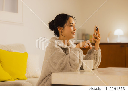 夜リビングでスマホを見る若い女性 夜リビングでスマホを見る若い女性 141191258