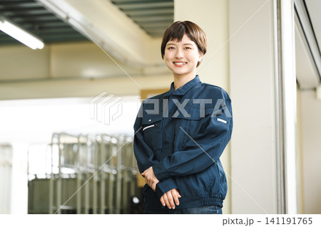 物流倉庫で働く作業服姿の若い女性 物流倉庫で働く作業服姿の若い女性 141191765