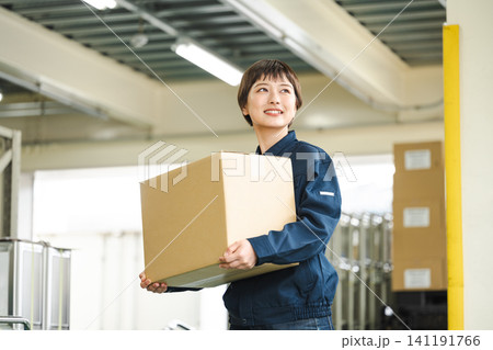 物流倉庫で働く作業服姿の若い女性 物流倉庫で働く作業服姿の若い女性 141191766