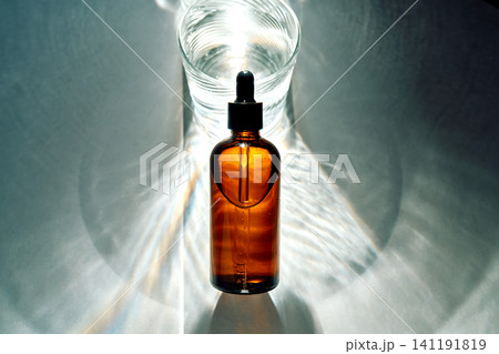 Amber dropper bottle and glass water with light reflections Amber dropper bottle and glass water with light reflections 141191819