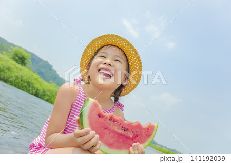 夏の川原でスイカを食べる女の子 141192039