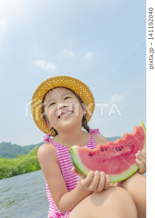 夏の川原でスイカを食べる女の子 141192040