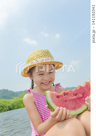 夏の川原でスイカを食べる女の子 141192041