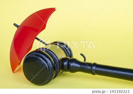 Judge gavel and red umbrella representing law, legal action, security and insurance with customizable space for text. Judge gavel and red umbrella representing law, legal action, security and insurance with customizable space for text. 141192221