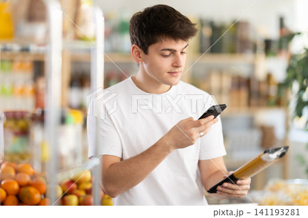 Young shopper using mobile app to pay for spaghetti in grocery store Young shopper using mobile app to pay for spaghetti in grocery store 141193281