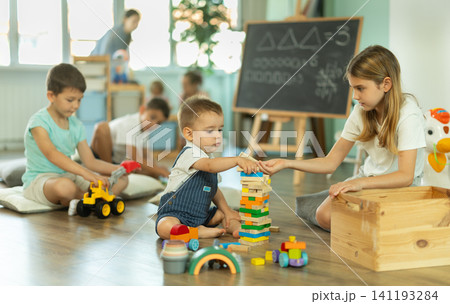 Boy and girl playing games in front of children in kindergarten Boy and girl playing games in front of children in kindergarten 141193284