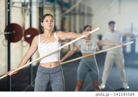 Young woman doing warm-up with stick Young woman doing warm-up with stick 141193584