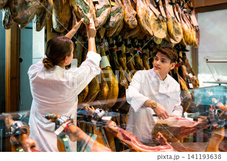 Young man and woman selling spanish jamon at counter 141193638