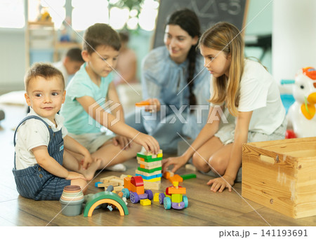 Children playing with toys with teacher nearby in kindergarten 141193691