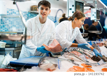 Positive salesman demonstrating tuna in fish store Positive salesman demonstrating tuna in fish store 141193742