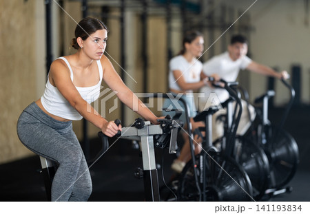 Young woman exercising on exercise bike in gym Young woman exercising on exercise bike in gym 141193834