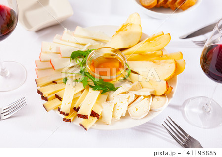 Plate with different types of cheese and cup of honey 141193885