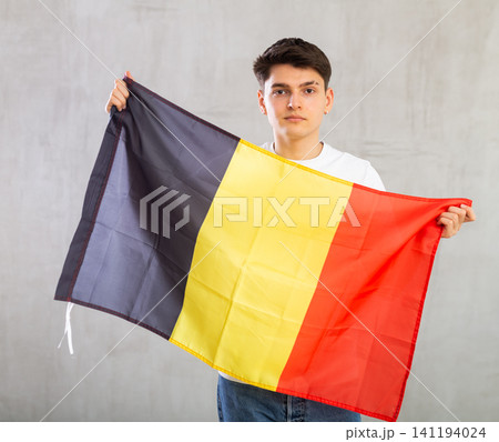 Focused young guy holding Belgium flag Focused young guy holding Belgium flag 141194024