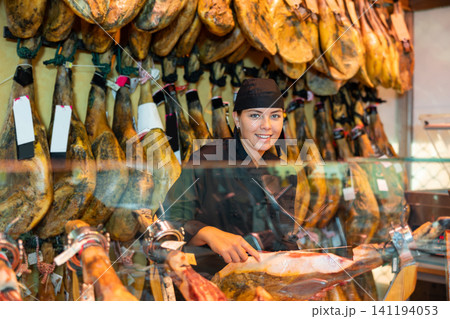 Female seller of butcher store preparing jamon of lamb for sale Female seller of butcher store preparing jamon of lamb for sale 141194053