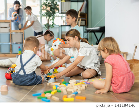 Children of different ages playing with toys inside playroom Children of different ages playing with toys inside playroom 141194146