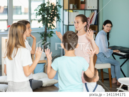 Children dancing in circle while teacher plays music on synthesizer Children dancing in circle while teacher plays music on synthesizer 141194171