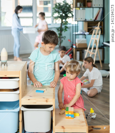 Little girl and older boy playing with wooden blocks on storage-shelf Little girl and older boy playing with wooden blocks on storage-shelf 141194173