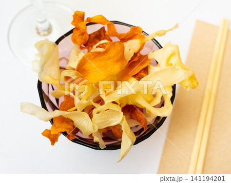Pile of vegetable chips of sweet potato and yuca in bowl Pile of vegetable chips of sweet potato and yuca in bowl 141194201
