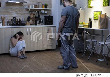 Injured woman sits on the floor after domestic violence, with bruised face, fear and partner aggression showing trauma and unsafe home conflict. Injured woman sits on the floor after domestic violence, with bruised face, fear and partner aggression showing trauma and unsafe home conflict. 141194500