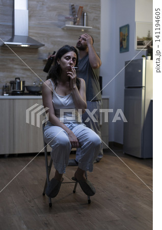 Unhappy bruised woman smokes in a kitchen after domestic violence, reflecting misery, physical abuse and harassment from a violent drunk husband. Unhappy bruised woman smokes in a kitchen after domestic violence, reflecting misery, physical abuse and harassment from a violent drunk husband. 141194605
