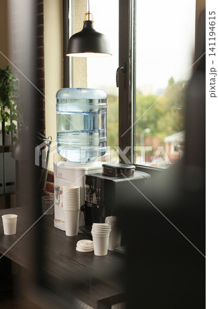 Water dispenser, coffee machine and refreshment station sit on a table in a modern brick wall office prepared for workplace breaks. Water dispenser, coffee machine and refreshment station sit on a table in a modern brick wall office prepared for workplace breaks. 141194615