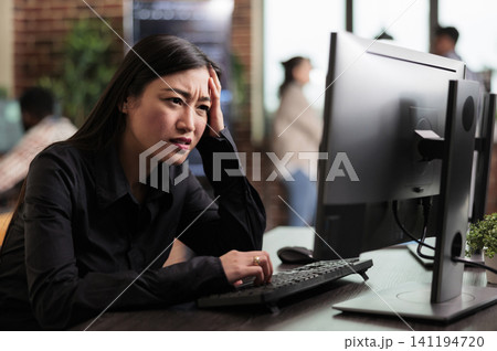 Asian computer engineer looks puzzled by a nonfunctional security algorithm, suggesting troubleshooting and problem solving during coding work. Asian computer engineer looks puzzled by a nonfunctional security algorithm, suggesting troubleshooting and problem solving during coding work. 141194720