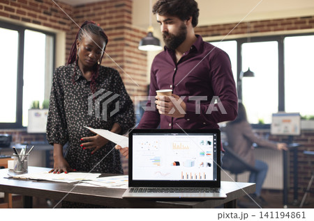 Pregnant businesswoman and male colleague review financial charts at an office desk, planning startup work and business presentation data. 141194861