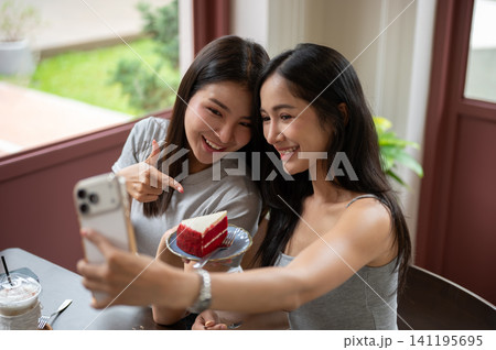 Asian women taking selfie together with red velvet cake during a cheerful cafe gathering with friend Asian women taking selfie together with red velvet cake during a cheerful cafe gathering with friend 141195695