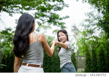 Beautiful Asian woman holding hands and pulling her friend to dance in the garden. 141195772