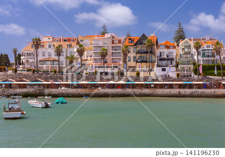 Colorful residential buildings and palm trees along the waterfront promenade in Cascais, Portugal. View of the historic seafront district on a sunny day. Colorful residential buildings and palm trees along the waterfront promenade in Cascais, Portugal. View of the historic seafront district on a sunny day. 141196230