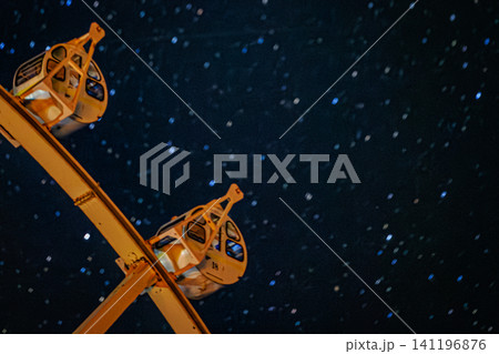 星の軌跡が流れるドラマチックな夜空に斜めに交差する上富良野町の観覧車のフレーム 星の軌跡が流れるドラマチックな夜空に斜めに交差する上富良野町の観覧車のフレーム 141196876