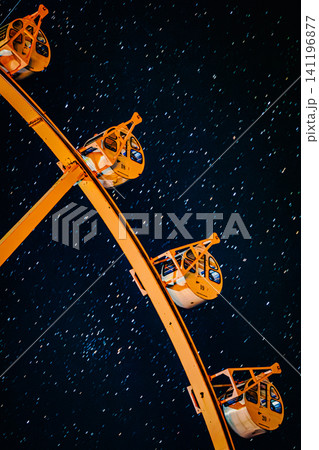 無数の星々が光の筋を描く夜空を背景に佇む深山峠アートパークの観覧車とゴンドラ 141196877