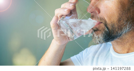 bearded man drinking a glass of ice water bearded man drinking a glass of ice water 141197288