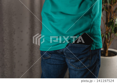 Man holds smartphone in pocket of jeans in casual setting at home 141197524