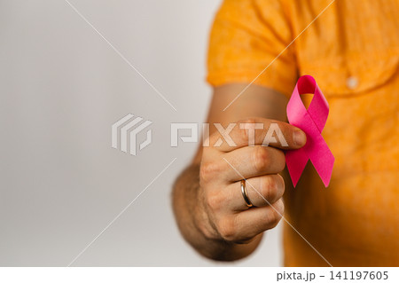Man holds pink awareness ribbon for health campaign and support Man holds pink awareness ribbon for health campaign and support 141197605