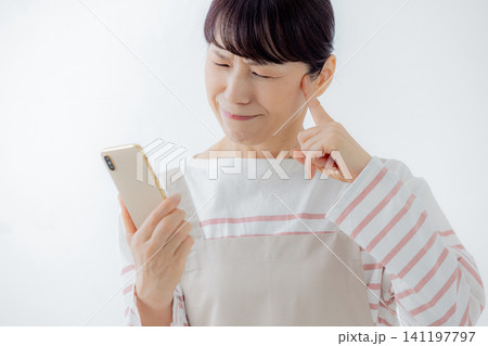 スマホを見て悩む主婦 スマホを見て悩む主婦 141197797