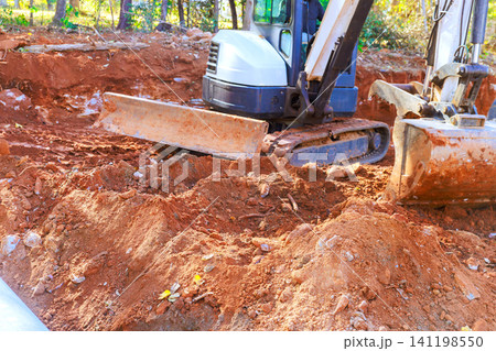 Construction equipment works on site to dig prepare ground for new building project Construction equipment works on site to dig prepare ground for new building project 141198550