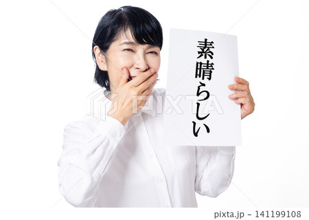 素晴らしいと書かれた紙を喜ぶ白いシャツを着た中年女性 素晴らしいと書かれた紙を喜ぶ白いシャツを着た中年女性 141199108