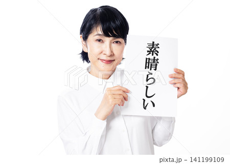 素晴らしいと書かれた紙を両手で持ち微笑む白いシャツを着た中年女性 素晴らしいと書かれた紙を両手で持ち微笑む白いシャツを着た中年女性 141199109