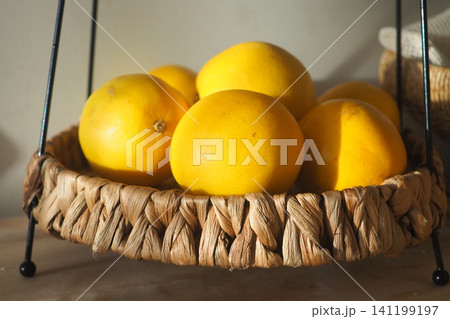 Fresh lemons in a woven basket on a table Fresh lemons in a woven basket on a table 141199197